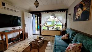 ein Wohnzimmer mit einem blauen Sofa und einem Fernseher in der Unterkunft Maison Bardot 1 - Casa em condomínio para 4 em Geribá, Búzios in Búzios