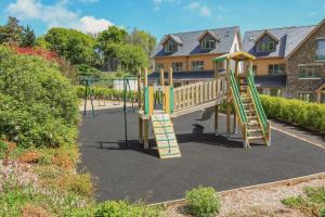 un parque infantil con un tobogán frente a una casa en Keepers Lodge, Hillfield Village, en Dartmouth