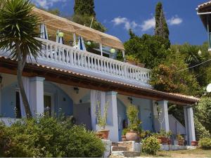 a house with a white balcony and a palm tree at Apartment in Mpenitses with Sea Views & Pool in Benitses