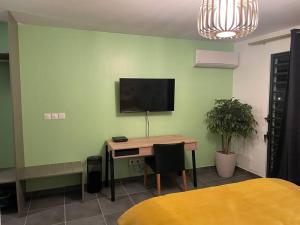 a room with a desk and a television on a wall at Studio d affaires Piscine rooftop in Cayenne