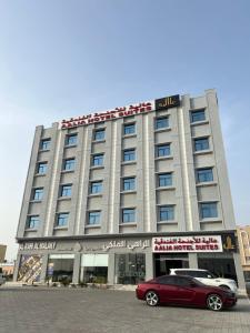 Aalia Hotel Suites في صحار: سيارة حمراء متوقفة أمام مبنى