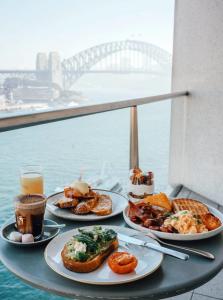a table with plates of food and drinks and a view of a bridge at Pullman Quay Grand Sydney Harbour in Sydney