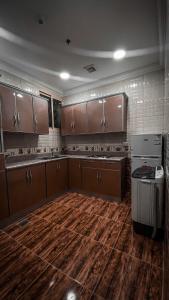 a large kitchen with wooden floors and wooden cabinets at Reef Al Qassim Hotel Apartments in Buraydah