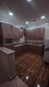 a large kitchen with brown cabinets and a wooden floor at Reef Al Qassim Hotel Apartments in Buraydah