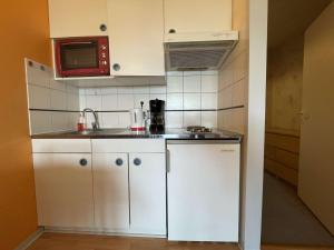una pequeña cocina con armarios blancos y microondas en Appartement La Rochelle, 1 pièce, 4 personnes - FR-1-246-629, en La Rochelle
