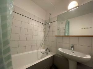 La salle de bains est pourvue d'un lavabo, d'une baignoire et d'un miroir. dans l'établissement Appartement La Rochelle, 1 pièce, 4 personnes - FR-1-246-629, à La Rochelle