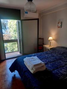 1 dormitorio con cama con sábanas azules y ventana en Hermoso dpto centrico externo c/ balcones en Córdoba