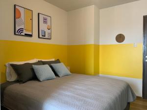 - une chambre avec des murs jaunes et blancs et un lit dans l'établissement Studio Memphis en El Prado con vista al Cristo!, à Cochabamba