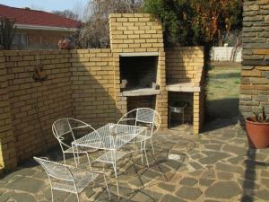 um pátio com uma mesa e cadeiras e um forno de tijolo em Bedrock Guesthouse em Bloemfontein
