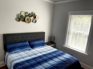 a bedroom with a bed with a blue comforter and two windows at Cozy & Quiet Two Bedroom Condo In The Heart Of Historic St. Augustine in St. Augustine