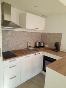 a kitchen with white cabinets and a sink at Charmant gîte avec jacuzzi privatif in Saint-Martin-Choquel