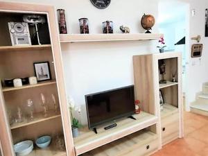 ein Fernseher in einem Bücherregal in einem Wohnzimmer in der Unterkunft Duplex in Urb Naturista near Beach & Pool in Playas de Vera