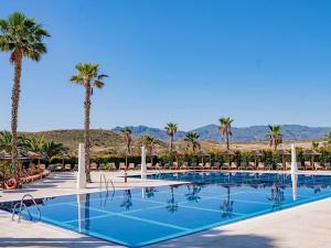 una gran piscina con palmeras y sillas en Belvilla by OYO Valle del Este las Yucas, en El Esparragal