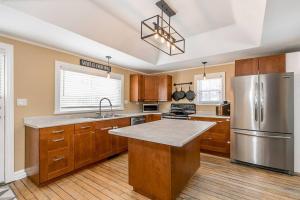 a kitchen with wooden cabinets and a stainless steel refrigerator at Kids Paradise! Chickens, Pool, Trampoline in Port McNicoll