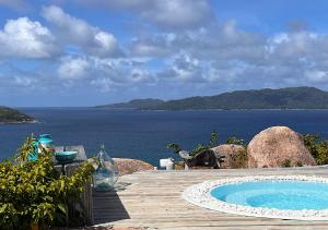 a swimming pool on a deck with a view of the ocean at Le Château de feuilles in Baie Sainte Anne