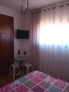 sypialnia z łóżkiem, stołem i oknem w obiekcie Lélé w mieście Vila Praia de Âncora