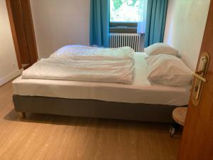 a bed with white sheets and pillows in a room at Pension Karlsdorfer Hof in Seeboden