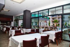 Un restaurante con mesas y sillas blancas y ventanas. en Green Garden Suites Hotel, en Alanya