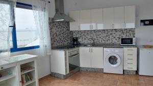 uma cozinha com armários brancos e uma máquina de lavar e secar roupa em APARTAMENTO ROQUE DEL ESTE em Orzola