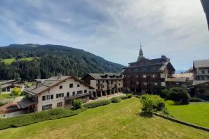 a group of buildings on a hill with a green field at Studio with balcony in the center of the village in Le Grand-Bornand