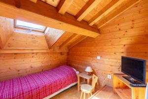 a bedroom in a log cabin with a bed and a tv at Quiet apartment near the slopes in La Clusaz