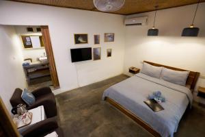 a bedroom with a bed and a television and a couch at Fisheye The Rooms - Room 2 in El Nido