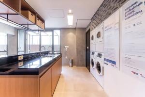 a laundry room with a washer and dryer on a wall at Studios Sampa - Moema Cotovia in Sao Paulo