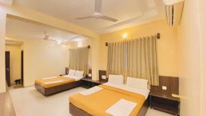 a hotel room with two beds and a window at Hotel Sai Gurusthan in Shirdi