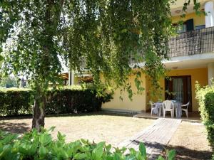 un giardino di fronte a una casa con un albero di Villa in Caorle near Spiaggia Tartaruga a La Fagiana