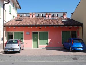 dos autos estacionados frente a un edificio rojo en Affittacamere Matteo, en Verona