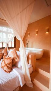 a bedroom with a tub and a bed with pillows at Terra Cottages Bali in Uluwatu