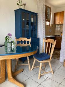einem Esstisch mit 2 Stühlen und einem blauen Schrank in der Unterkunft Apartments Mimoza Komiza in Komiža