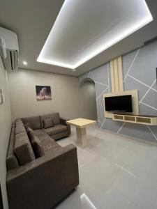 Aalia Hotel Suites في صحار: غرفة معيشة مع أريكة وتلفزيون