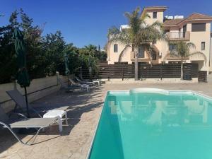 a swimming pool with two chairs and a building at Artemis Executive Suite in Larnaca +14 photos