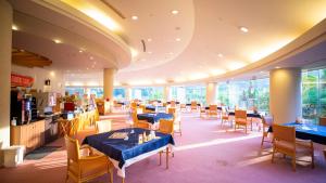 un restaurante con mesas y sillas azules y ventanas en Kamogawa Country Hotel, en Kamogawa
