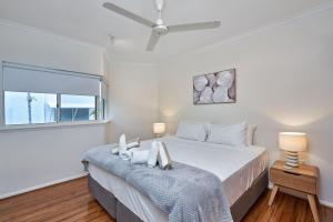 een witte slaapkamer met een bed en een raam bij Beachfront On Arlington in Clifton Beach