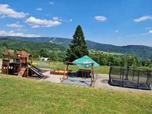 un parque infantil con columpio y sombrilla en Hotel PAM, en Jáchymov