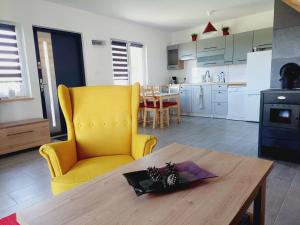 a kitchen with a yellow chair and a wooden table at JESZCZE BARDZIEJ DZIKI SAD in Słajszewo +14 photos