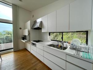 una cucina con armadi bianchi, lavandino e finestra di 伊東温泉 Working Base Izu-Ito a Ito