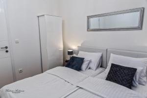 a white bed with two blue pillows and a mirror at Urbana Villa Four season in Zagreb