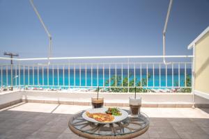 a table with a plate of food on a balcony with the ocean at Monato Luxury Apartments in Agios Nikitas