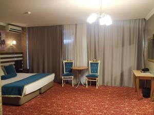 ein Hotelzimmer mit einem Bett, 2 Stühlen und einem Tisch in der Unterkunft Gallery Hotel Baku in Baku
