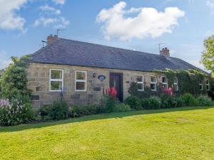 una casa de piedra con césped delante en Barnacre, en Morpeth