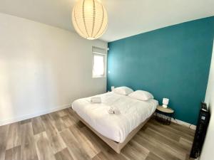 ein Schlafzimmer mit einem weißen Bett und einer blauen Wand in der Unterkunft Comme chez soi , Déplacement Pro in Mondeville