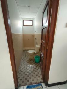 a bathroom with a toilet and a window and a door at Airtown Guest House in Jetis