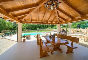 pérgola de madera con mesa de madera y piscina en Villa Green Pearl, en Gostinjac