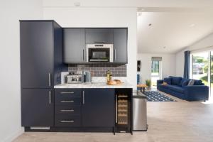 a kitchen with black cabinets and a blue couch at Buttercup Lodge, 33 Roadford Lake Lodges in Lifton