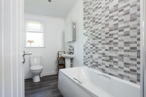 ein weißes Badezimmer mit Badewanne und Toilette in der Unterkunft Buttercup Lodge, 33 Roadford Lake Lodges in Lifton + 15 Fotos