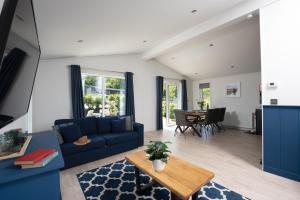 a living room with a blue couch and a table at Buttercup Lodge, 33 Roadford Lake Lodges in Lifton