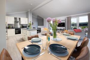uma sala de jantar e cozinha com mesa e cadeiras em Clover Lodge, 32 Roadford Lake Lodges, Lifton em Lifton